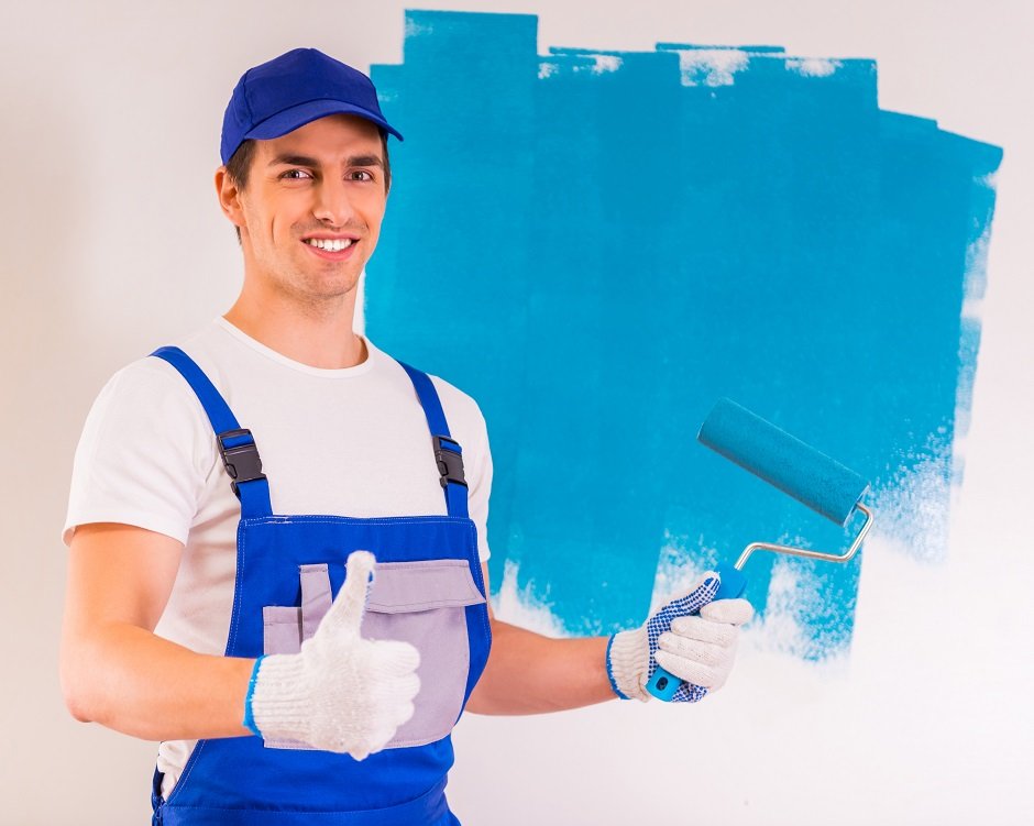 Male painter paints a wall and shows thumb up.